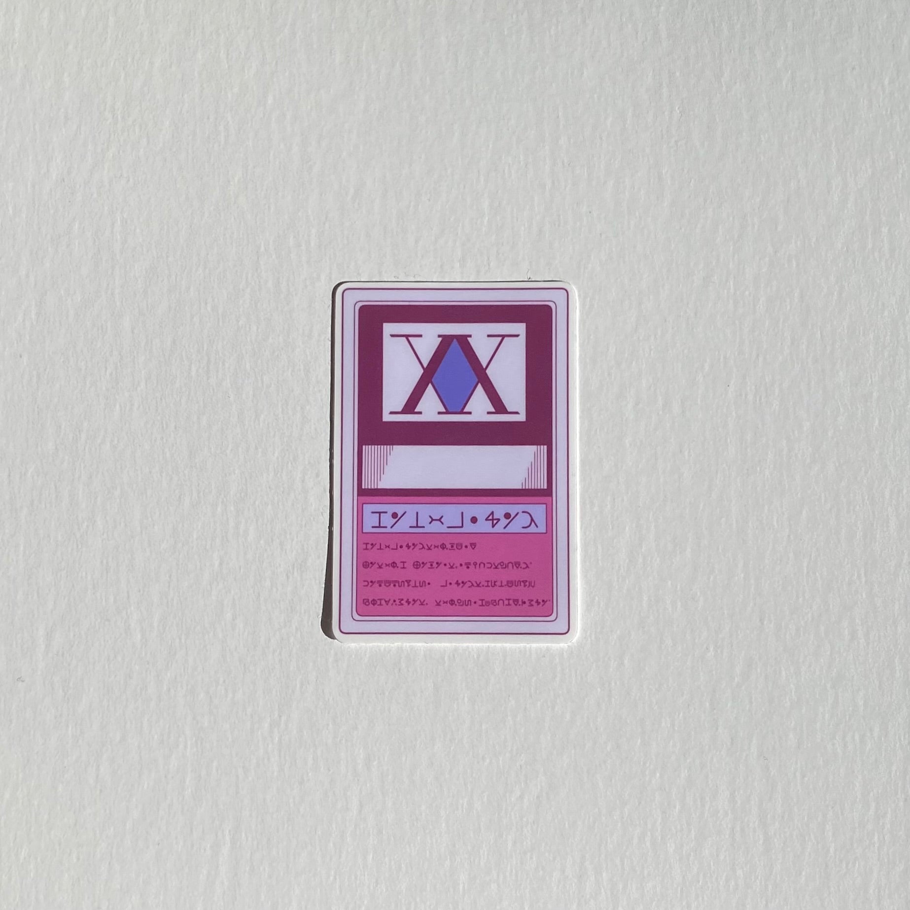 Hunter x Hunter merch. Hunter license sticker in purple and pink. Anime merchandise. White background.